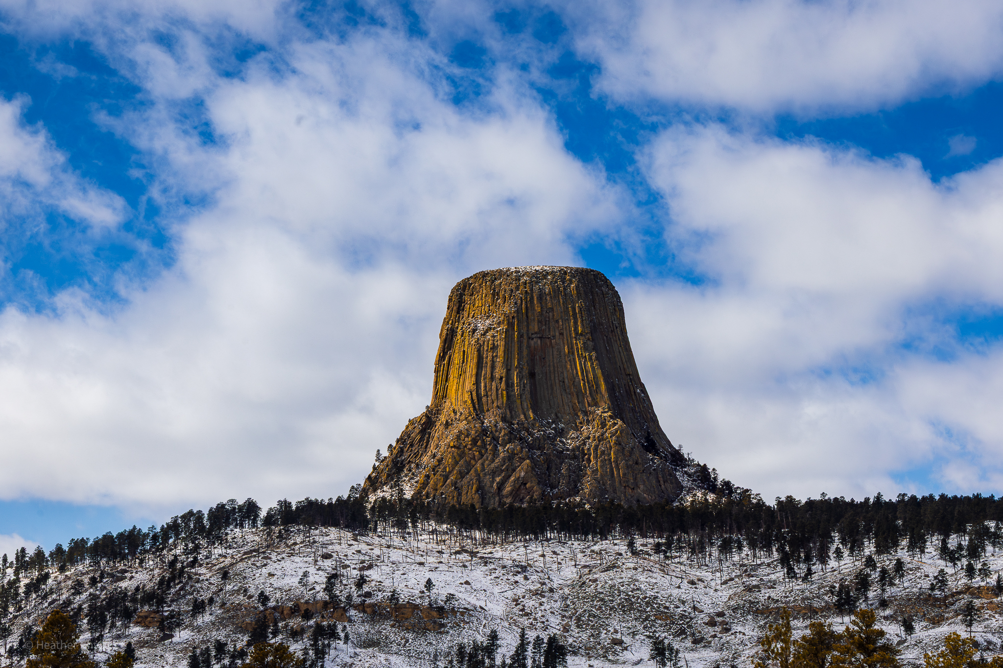 Igneous butte monolith Devil's Tower in a snowy scene bathed in warm golden light